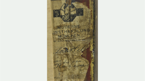 Detail der Rückseite des Gemäldes von Dora Hitz, Papieraufkleber mit dem Aufdruck des Signets (In Arte Libertas) „Moderne Kunsthandlung München, Goethestraße 64“ und handschriftlicher Vermerk „Dora Hitz“, In den Rosen“